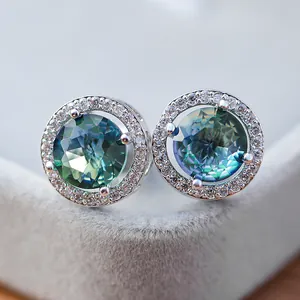 Vue macro de boucles d'oreilles halo en argent avec topaze mystique et zircons brillants
