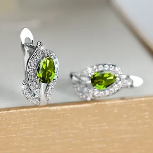 Detailopname van zilveren oorringen met druppelvormige groene zirkonia stenen erin