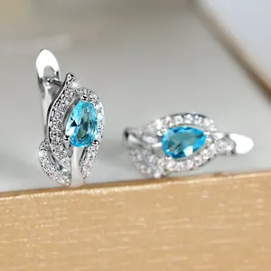 Macro-opname van zilveren druppeloorbellen met blauwe edelstenen en fonkelende diamanten