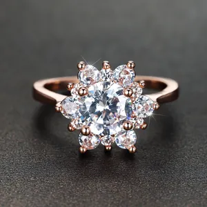 Rose gold flower ring with central stone and crystal accents on textured background