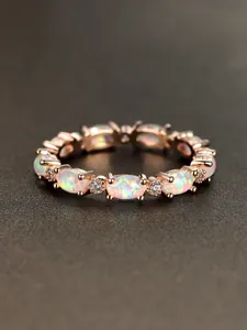 Macro shot of rose gold ring with oval opals and sparkling zircon stones detailing