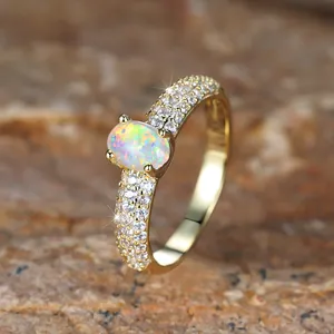 Golden oval white opal ring with four-prong setting and micro-pave crystals