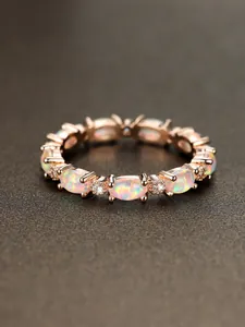 Detailed macro view of rose gold ring with oval opal stones and micro-set cubic zirconia