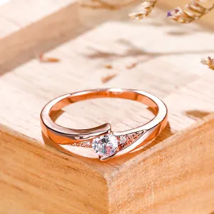 Detailed macro of rose gold ring with round brilliant cut stone on wooden stand