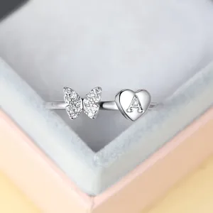 Détail d'une bague papillon argentée avec cristaux et design cœur lettre A