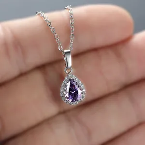 Close-up of a silver pear-cut purple gemstone pendant with a halo of white diamonds