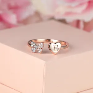 Détail de la bague en or rose avec papillon en zircon et breloque cœur avec lettre B