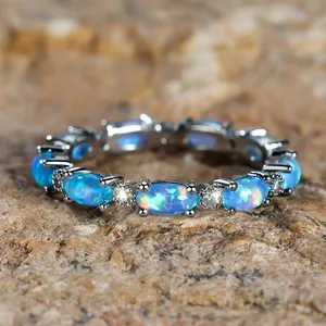 Elegant gold oval white opal ring with cubic zirconia stones on a natural rock background