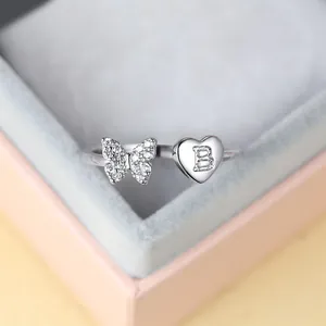 Détail d'une bague papillon dorée avec zircons et cœur gravé de la lettre B en gros plan