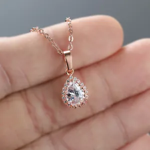 Macro shot of rose gold teardrop pendant with clear center stone and pave accents