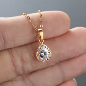 Detailed close-up of a pear-shaped teardrop pendant with halo setting in gold finish