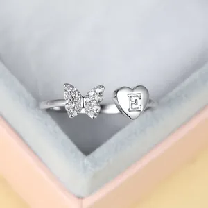 Détail macro bague argentée avec papillon en zircons et cœur gravé de la lettre E