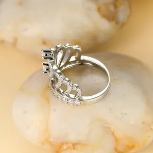 Vue détaillée d'une bague couronne en argent avec zircons sur des galets lisses