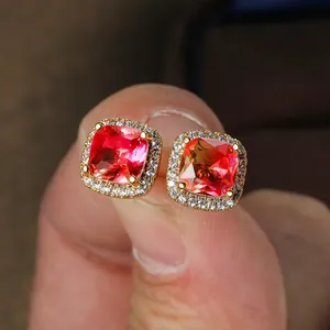 Detailed macro of gold square studs with a red cushion-cut gem and zircon halo