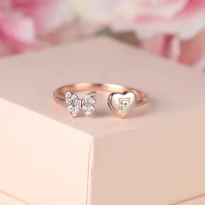 Gros plan sur bague or rose avec papillon en pavé de diamants et cœur gravé de la lettre F