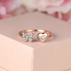 Détail de la bague en or rose avec papillon en zircon et pendentif cœur lettre G