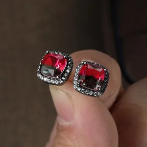 Macro view of square halo stud earring with red gemstone and micro-pave crystals
