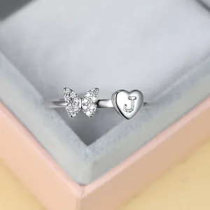Gros plan bague papillon argentée avec breloque cœur lettre J et zircons brillants