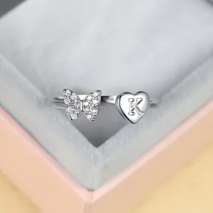 Détail de bague ajustable argentée avec papillon en zircon et cœur gravé lettre K