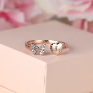 Détail de bague papillon or rose présentant un cœur en cristal et la lettre L