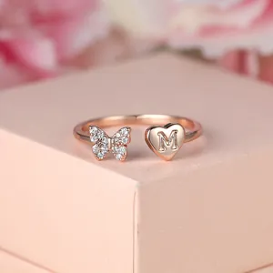 Gros plan sur bague papillon en or rose avec cœur en zircon et lettre M gravée
