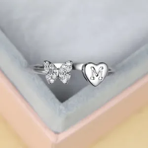 Vue détaillée d'une bague papillon argentée avec cristaux et cœur gravé d'une lettre M