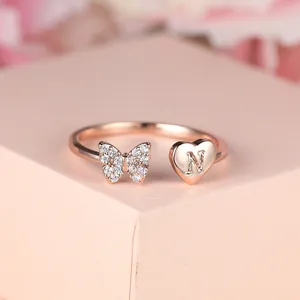 Détail bague or rose avec papillon en zircone et breloque cœur gravée de la lettre N
