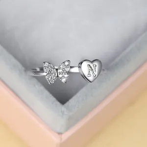 Vue rapprochée d'une bague argentée avec papillon diamanté et cœur gravé de la lettre N