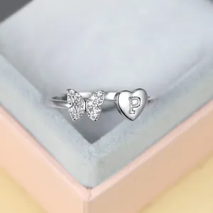 Détail de bague papillon argentée avec lettre P gravée sur un cœur en métal