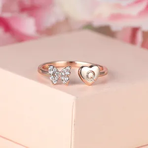 Détail de la bague or rose avec papillon étincelant et cœur gravé de la lettre Q