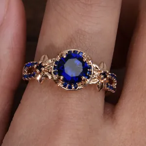Detalle macro de anillo vintage en oro rosa con piedra redonda azul y hojas finas