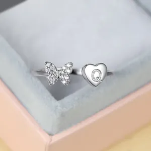 Détail de la bague ajustable en argent avec papillon scintillant et breloque coeur Q