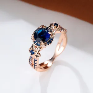 Detalle macro de anillo de oro rosa con piedra azul redonda y acentos de zafiro floral