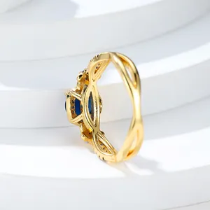Primer plano de un anillo de oro rosa con gema azul ovalada y banda trenzada hueca