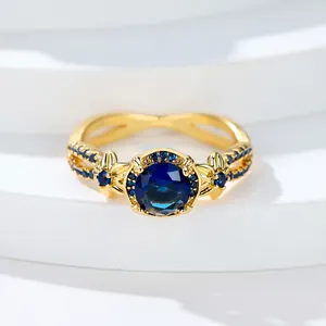 Anillo de oro rosa con piedra redonda azul real y detalles de banda filigrana floral