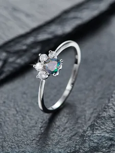 Primer plano de anillo de plata con circón azul corazón y detalle de huella de pata