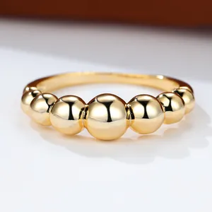 Anello dorato minimalista con sette sfere metalliche lucide su uno sfondo bianco