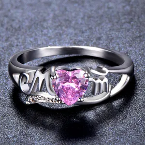 Macro shot of silver ring with Mom lettering and heart-shaped pink gemstone detail