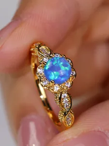 Macro detail of vintage floral ring with round blue opal and gold lace twisted band