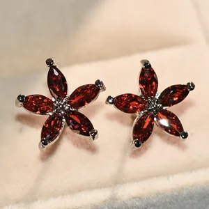Gros plan sur des boucles d'oreilles fleur en argent avec pétales rouges et cœur noir
