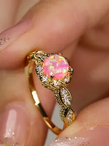 Macro shot of vintage lace flower ring featuring pink fire opal and gold plating