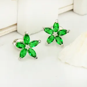 Détail macro de boucles d'oreilles fleur en argent avec cinq pétales en cristal vert