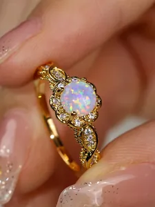 Macro shot of white opal flower ring with gold plating and intricate lace hollow design