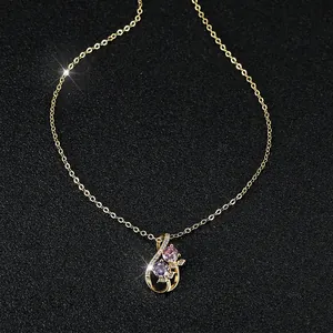 Elegante goldene Tulpenhalskette mit rosa und lila Kristallen auf schwarzem Hintergrund
