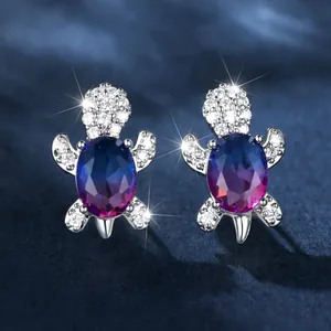 Dettaglio macro di orecchini a tartaruga in argento con gemma blu e zirconi micro-pavé
