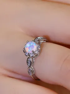 Macro shot of silver lace ring with white opal center and sparkling zircon halo