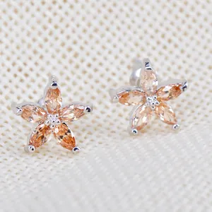 Boucles d'oreilles pétales champagne avec cristaux marquise sur fond de tissu beige