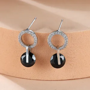Vue détaillée des boucles d'oreilles en argent avec zircons blancs et cristal noir rond