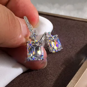 Detalle de pendientes colgantes de circón talla esmeralda con ganchos plateados