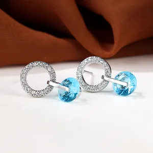Vue détaillée de boucles d'oreilles créoles argentées avec zircons bleu clair